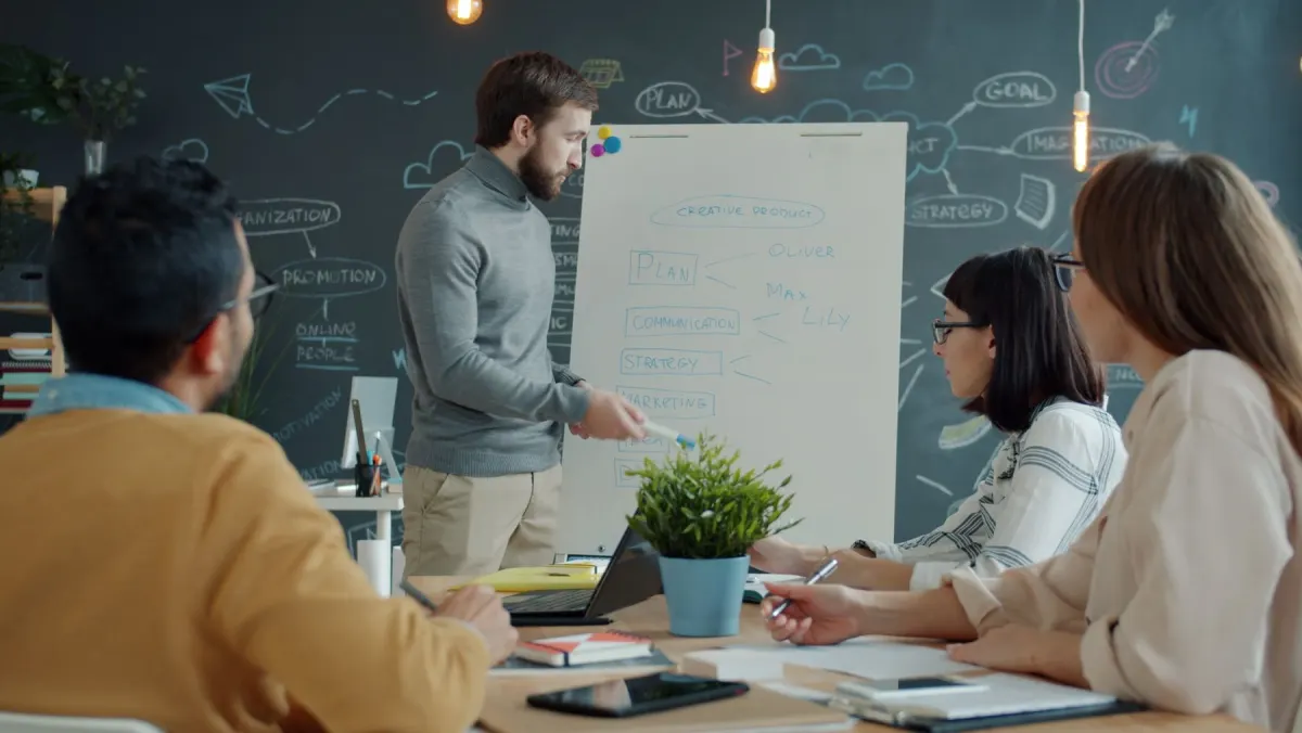Small marketing agency team in a planning session at a whiteboard